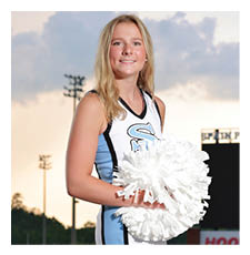 A cheerleader in a blue and white uniform stands on a football field holding a pom pom. AI generated content