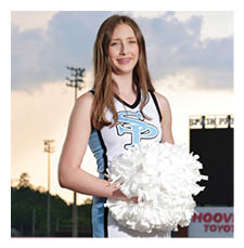 A cheerleader in a blue and white uniform stands on a football field holding a white pom pom. AI generated content