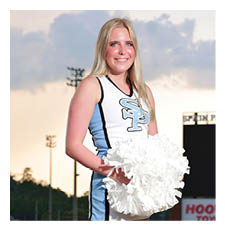A cheerleader in a blue and white uniform stands on a football field holding a pom pom. AI generated content