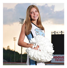 A cheerleader in a blue and white uniform stands on a football field. AI generated content