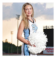 A cheerleader in a blue and white uniform stands on a football field holding a pom pom. AI generated content