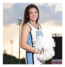 A cheerleader in a blue and white uniform stands on a field holding a pom pom. AI generated content