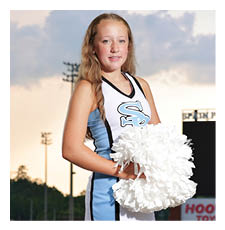 A young girl wearing a cheerleader outfit stands on a football field holding a pom pom. AI generated content
