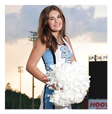 A cheerleader in a blue and white uniform stands on a football field holding a pom pom. AI generated content