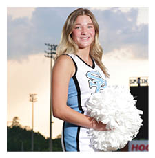A cheerleader in a blue and white uniform stands on a football field holding a pom pom. AI generated content