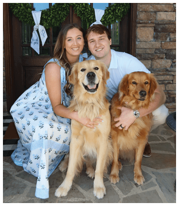 A man and woman pose with two dogs in front of a brick wall. AI generated content