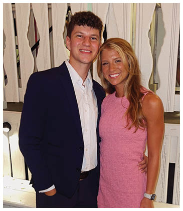 A man and woman are standing together, both wearing suits. The woman is wearing a pink dress. AI generated content