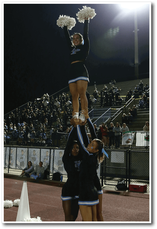 Three cheerleaders perform a stunt on a football field. AI generated content