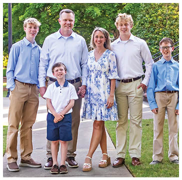 A family posing for a picture in front of a tree. AI generated content