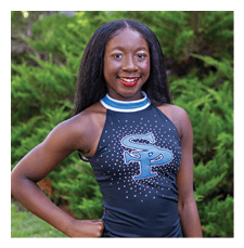A young woman wearing a black and blue cheerleading outfit stands in a grassy area. AI generated content