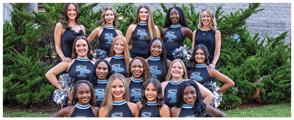 A group of cheerleaders pose for a photo in front of a bush. AI generated content