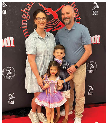 A man, woman, and two children pose for a picture in front of a stage. AI generated content