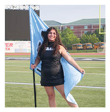 A woman in a black dress stands on a football field holding a blue flag. AI generated content
