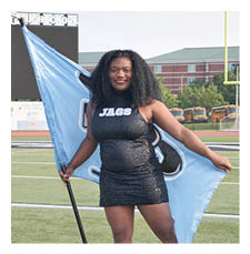 A woman in a black and blue dress holds a blue flag on a football field. AI generated content