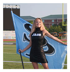 A woman in a black dress holds a blue flag on a football field. AI generated content