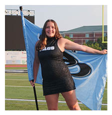 A woman in a black dress holds a blue flag while standing on a football field. AI generated content