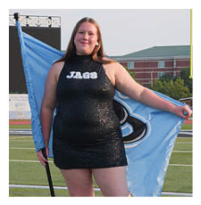 A woman in a black and blue dress holds a flag on a football field. AI generated content
