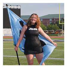 A woman in a blue dress holds a blue flag while standing on a field. AI generated content