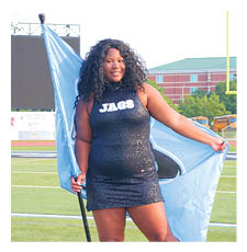 A woman in a black and blue dress holds a flag on a football field. AI generated content
