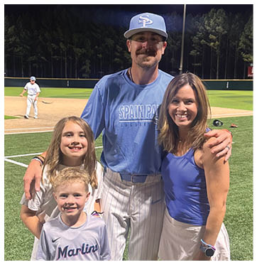 A man and woman pose with two children on a baseball field. AI generated content
