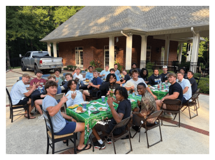 A group of people are sitting around a table outside, enjoying a meal together. AI generated content