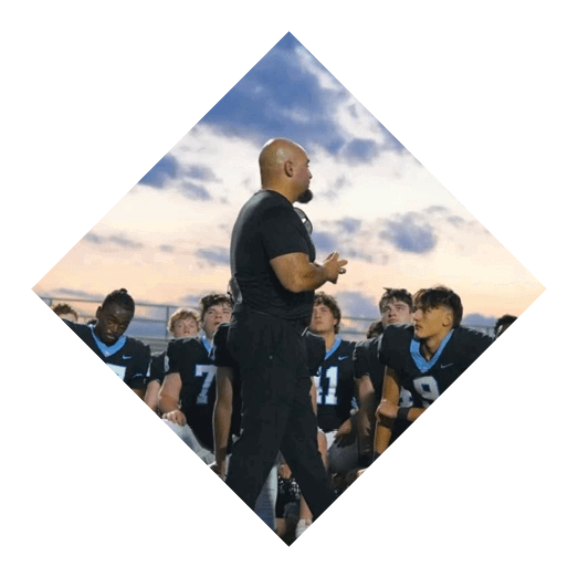 A man in a black shirt is talking to a group of young men. AI generated content