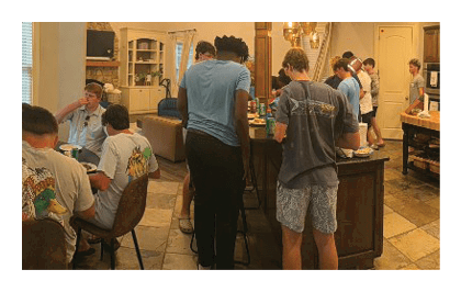 A group of people are gathered in a kitchen, standing around a counter. AI generated content