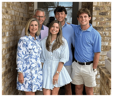 A family of four poses for a photo in front of a brick wall. AI generated content