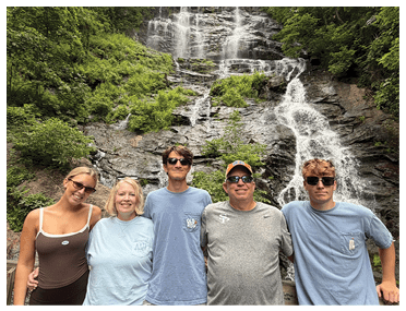 A group of five people, including a woman and four men, pose for a picture in front of a waterfall. AI generated content