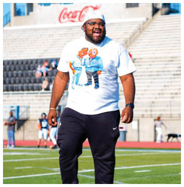 A man wearing a white shirt and black pants is standing on a football field. AI generated content