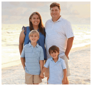 A man, woman, and two children pose for a photo on a beach. AI generated content