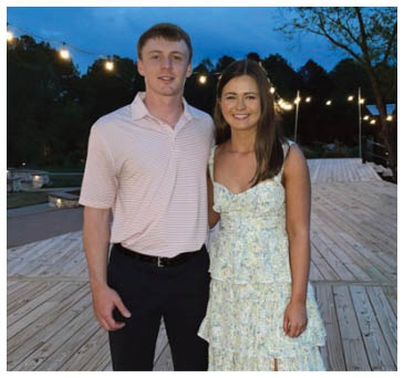 A man and woman pose for a picture on a wooden deck. AI generated content
