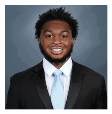 A young man wearing a suit and tie is smiling for the camera. AI generated content