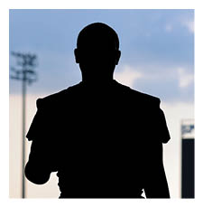 A football player is standing on a field holding a helmet. AI generated content