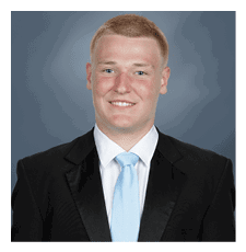 A young man wearing a suit and tie is smiling for the camera. AI generated content