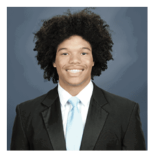 A young man wearing a suit and tie is smiling for the camera. AI generated content