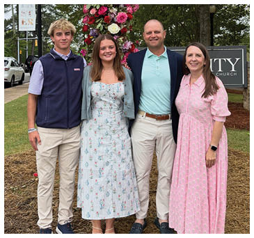 A group of four people, two men and two women, pose for a picture in front of a large cross. AI generated content