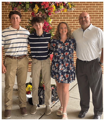 A family poses for a photo in front of a flower arrangement. AI generated content