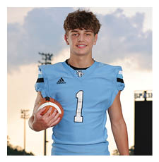A young man wearing a football uniform stands on a field holding a football. AI generated content
