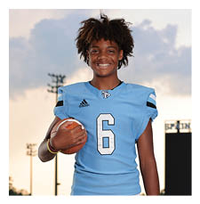 A young boy wearing a football uniform and holding a football. AI generated content