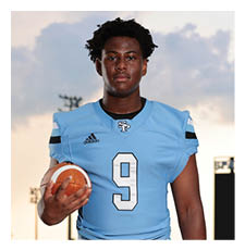 A football player wearing a blue and white uniform stands on a field holding a football. AI generated content
