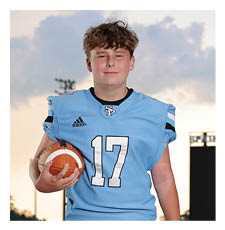 A young boy wearing a football uniform stands on a field holding a football. AI generated content