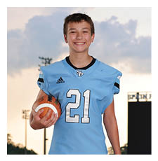 A young man wearing a football uniform stands on a field holding a football. AI generated content