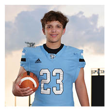 A football player in a blue uniform stands on a field holding a football. AI generated content