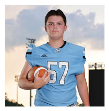 A football player wearing a blue jersey and white pants stands on a field holding a football. AI generated content