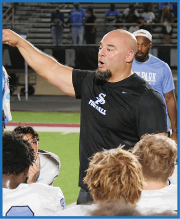 A man in a black shirt is pointing at a group of people, including a woman in a blue shirt. The group appears to be listening to the man's instructions. AI generated content