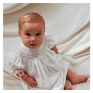A baby wearing a white dress is lying on a bed. AI generated content