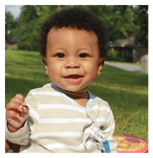 A young child is sitting on a blanket in a grassy area, smiling and wearing a striped shirt. AI generated content