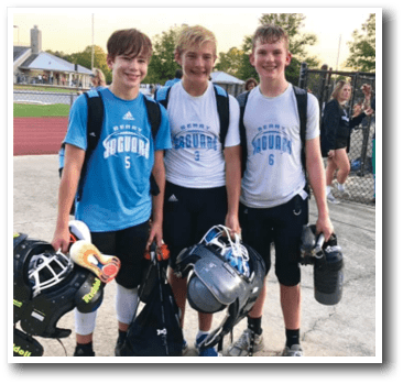 Three young boys wearing blue and white uniforms are standing together on a field, each holding a helmet. They are likely part of a sports team. AI generated content