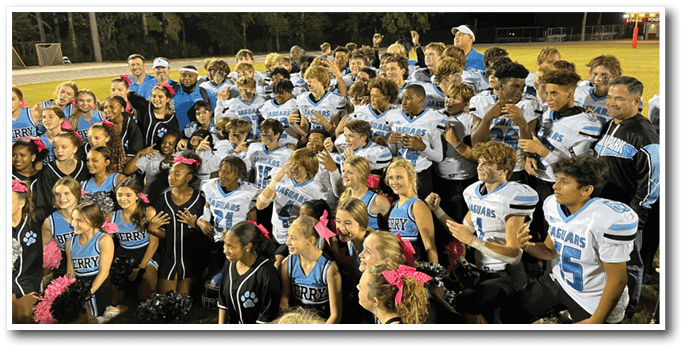 A group of cheerleaders and football players pose for a photo on the field. AI generated content